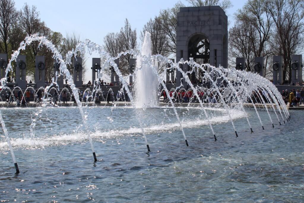 fountains spray n arches in front of arched pillar monument