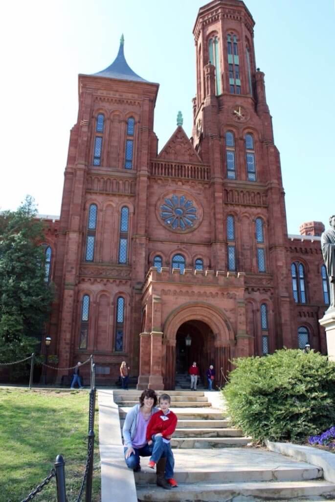 Mom holds little boy in front of red-tinted castle