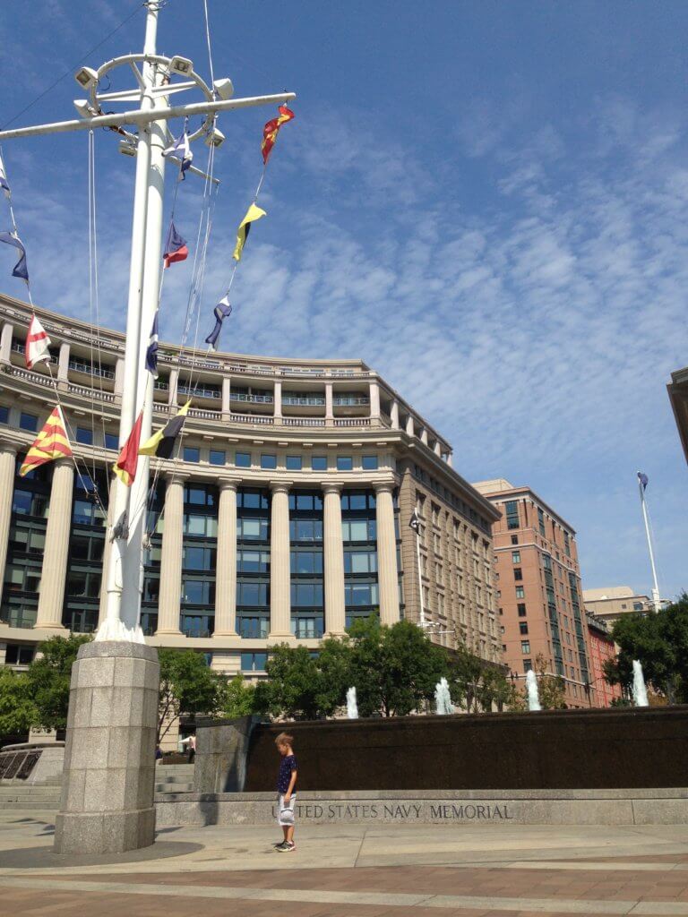 Little boy stands beside massive flag mast