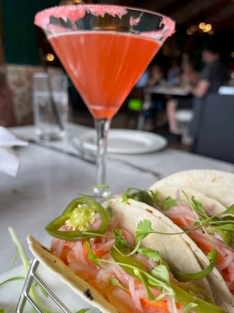 pink martini behind pink shrimp tacos with jalepenos on top