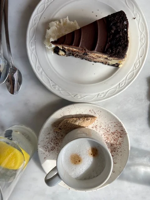 flat lay of cappuccino, biscotti, and chocolate cheesecake