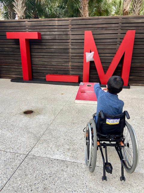 boy in wheelchair playing corn hole