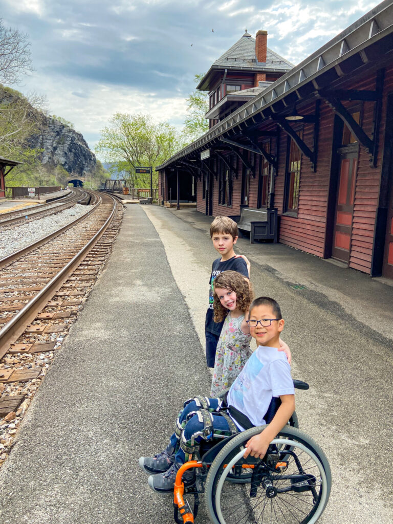 two brothers (one in a wheelchair) and a sister in front of a train station