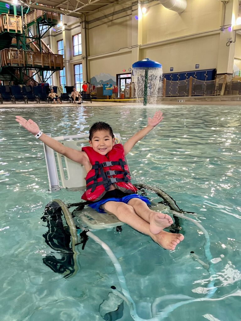 young boy in waterproof wheelchair inside wave pool