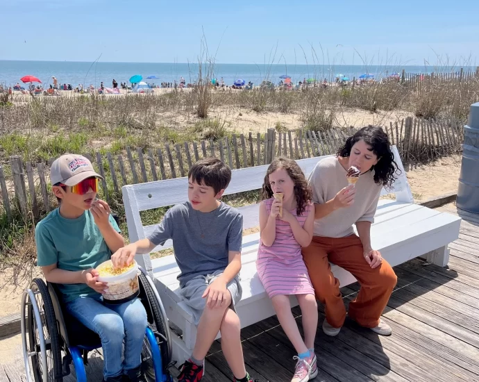 boy in wheelchair with family on bench at boardwalk