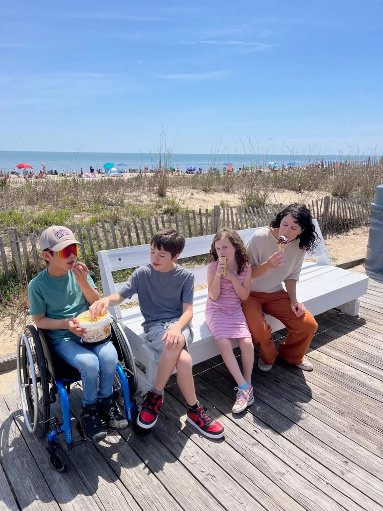 boy in wheelchair with family on bench at boardwalk