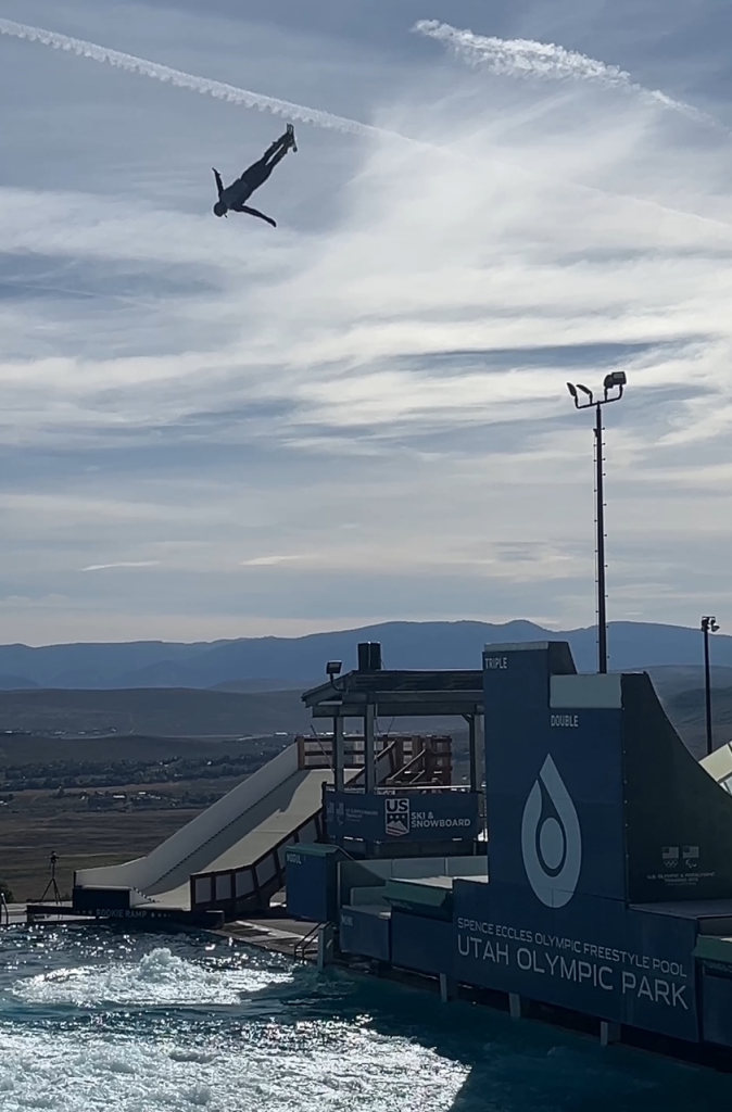 Man on skis upside down in the air over water.
