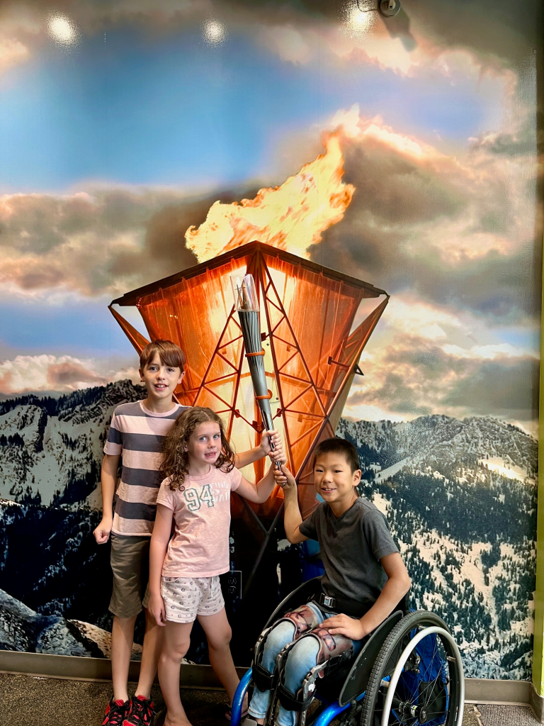 Two boys, one in a wheelchair, and their sister hold the olympic torch.
