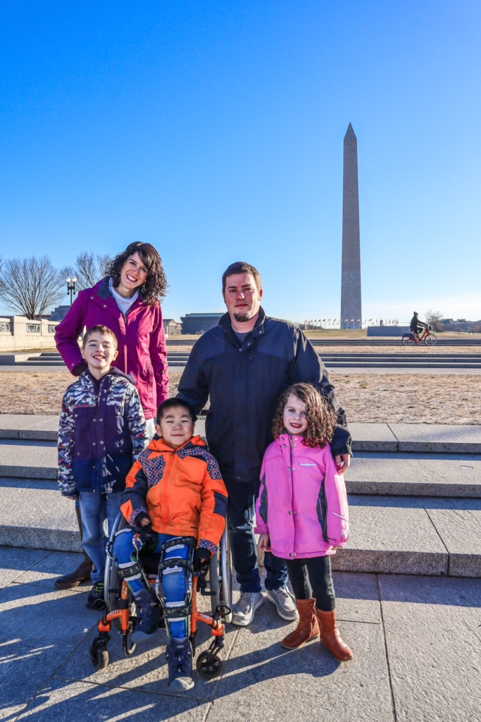 family smiling at camera in winter coats - washington monument in the background