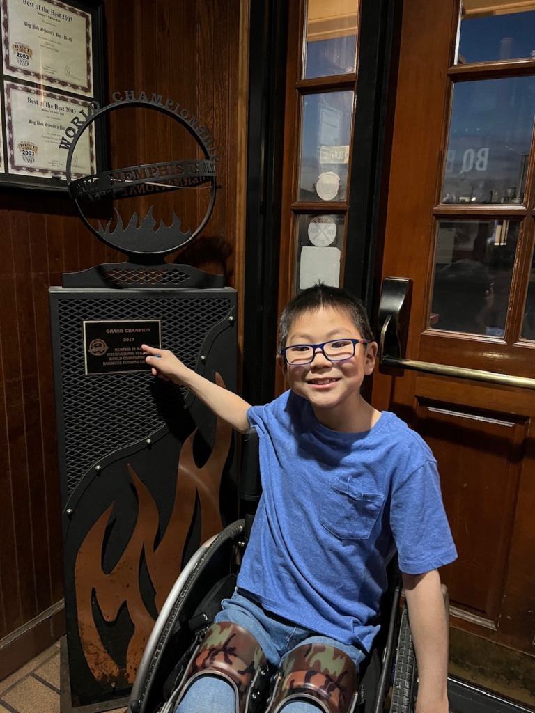 little boy in wheelchair points to large trophy