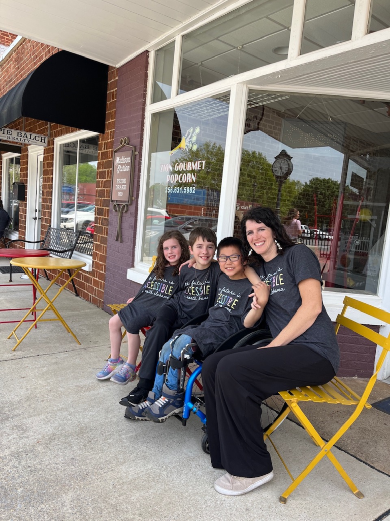 family seating in colorful chairs and smiling at camera on street lined with shops