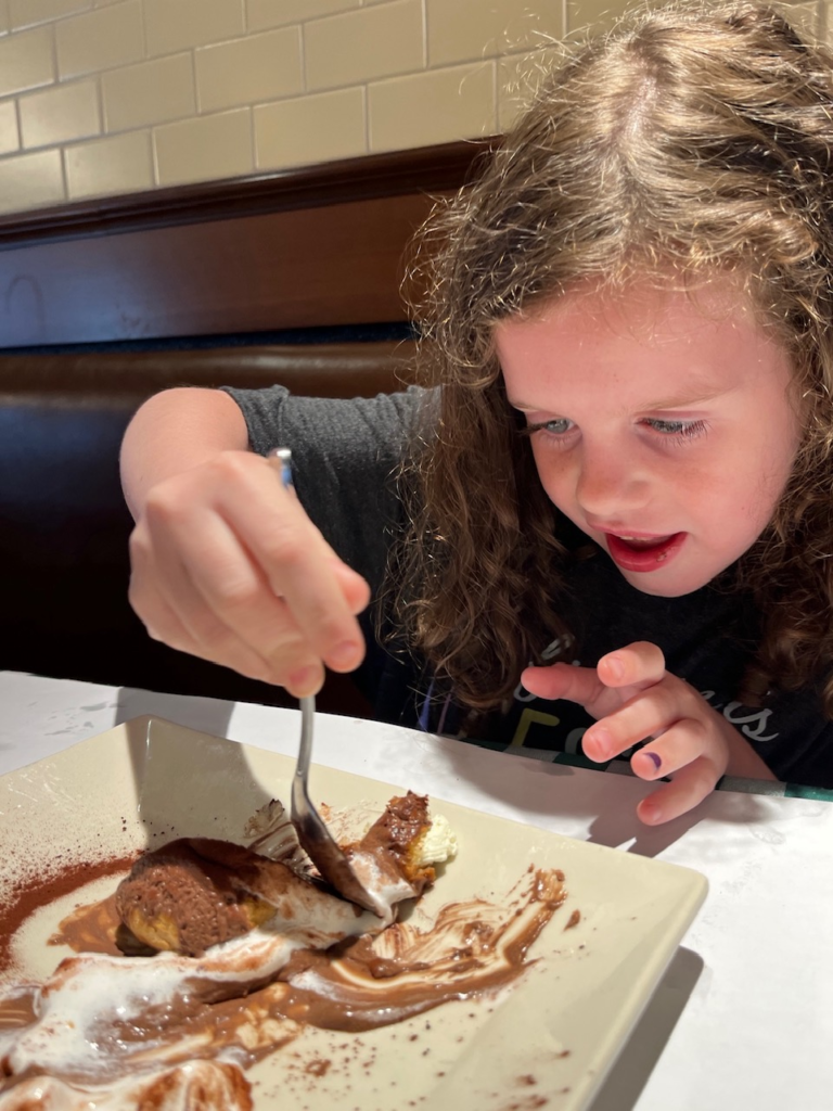 little girl smiling as she scoops chocolate off of her plate