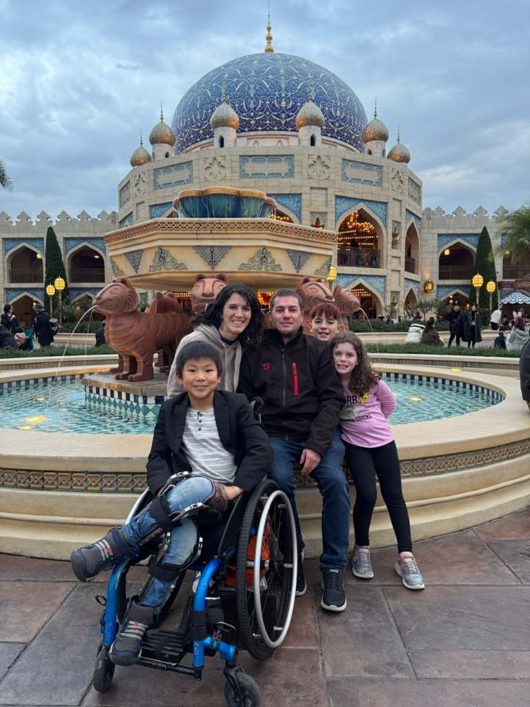 Allen family smiles at the camera with a middle eastern style carousel in the shape of a palace in the background.