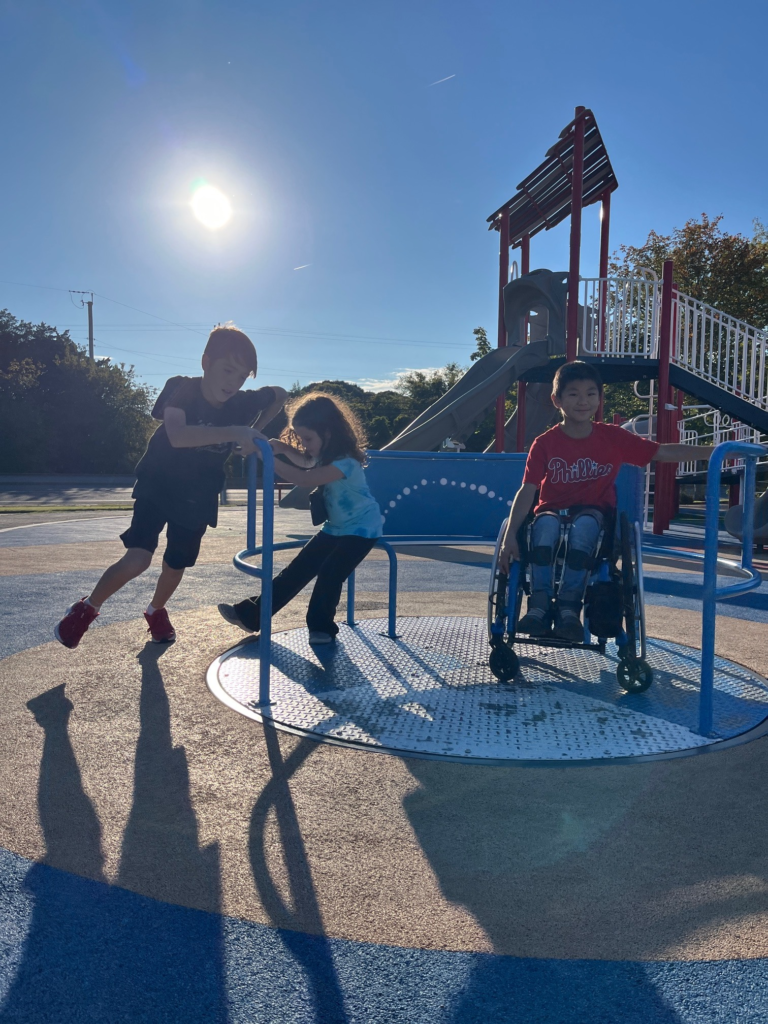 three kids, including one in a wheelchair, on accessible carousel