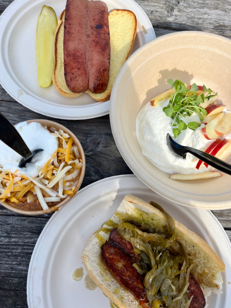 hot dog, yogurt parfait, chili with cheese, and sausage sandwich with peppers and onions - flat lay