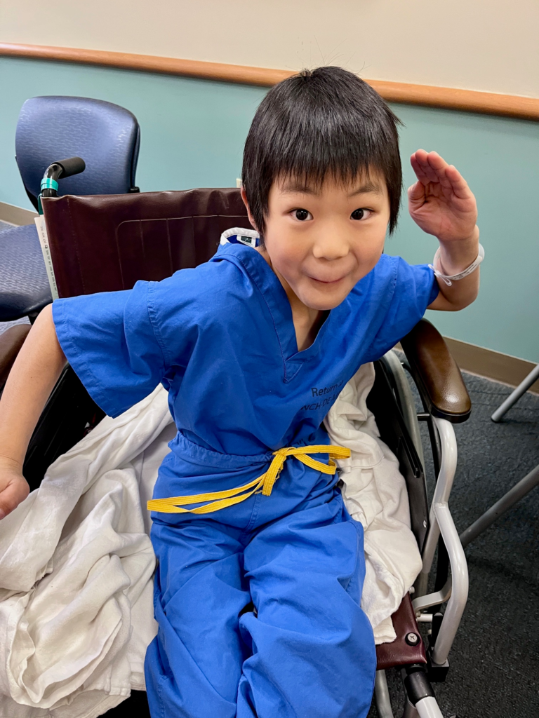 little boy in ninja pose in hospital scrubs in wheelchair
