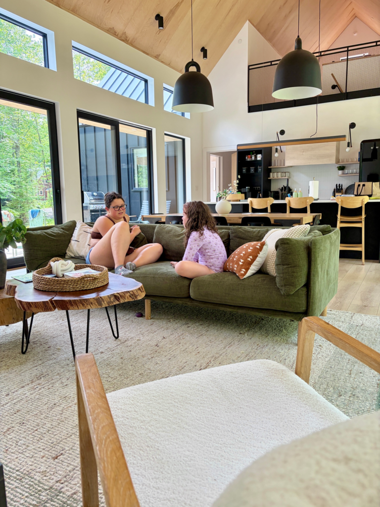 two girls talking on green couch in stylish, spacious cabin living room