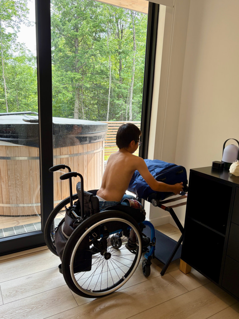 little boy in wheelchair putting his suitcase of luggage rack