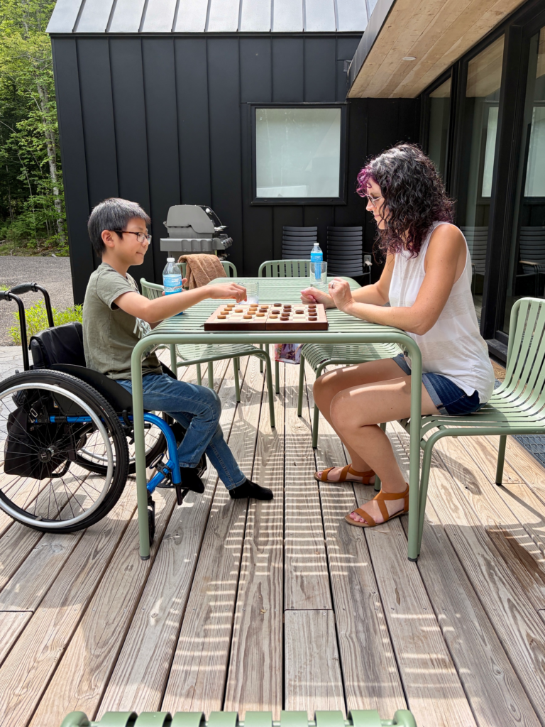 little boy in wheelchair playing mom at checkers on the deck