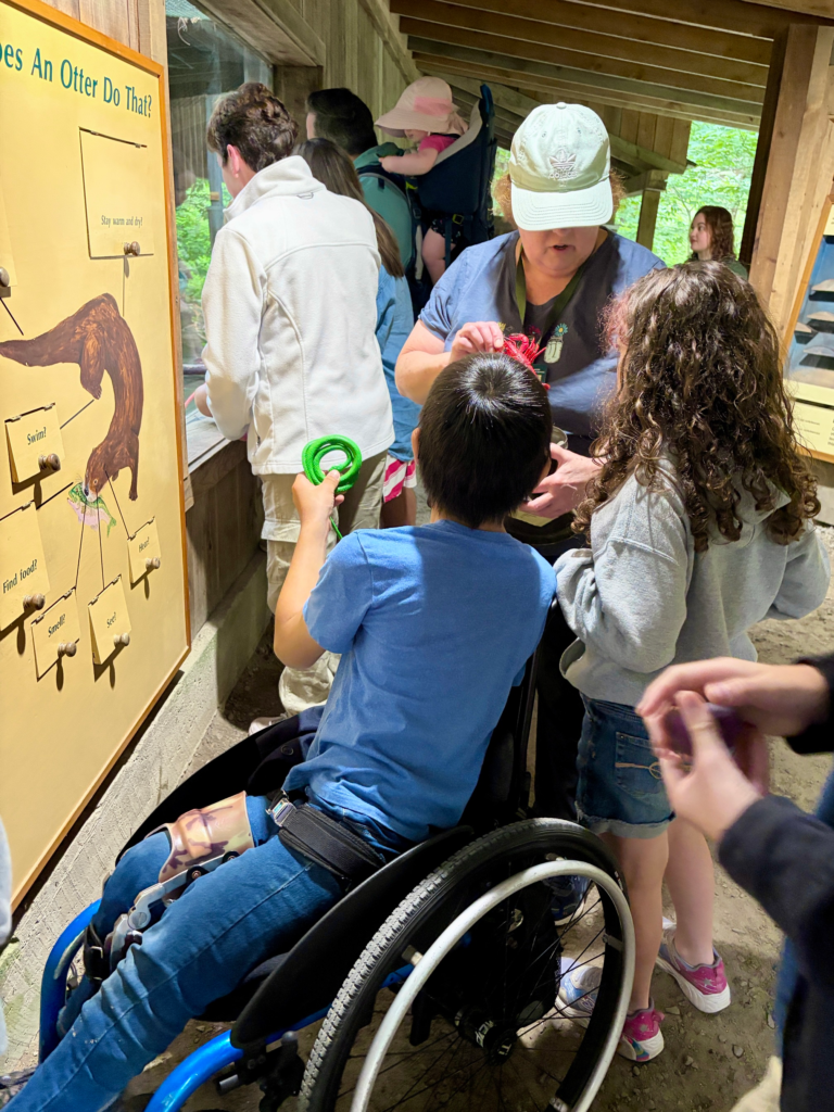 woman holds out exhibit items for children to touch