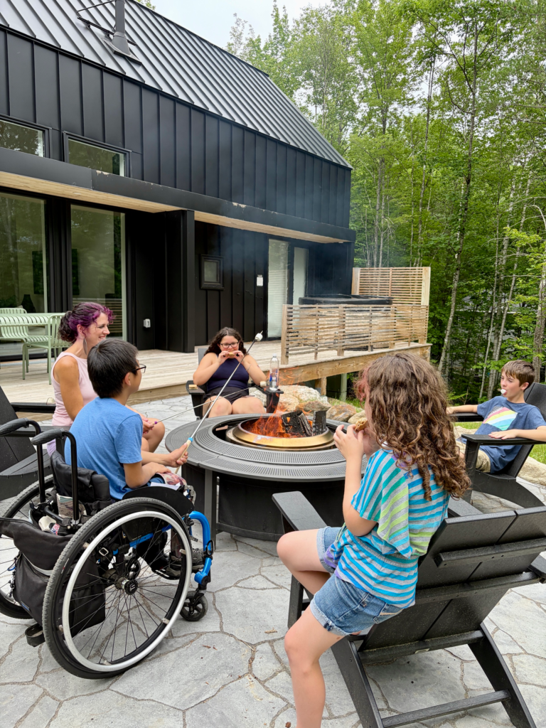 children make s'mores around the fire, including boy in wheelchair