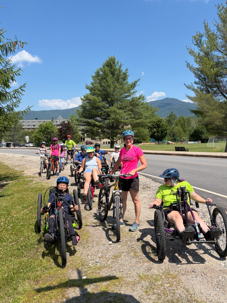 riders on adaptive bikes smile for the camera with mountains in the background